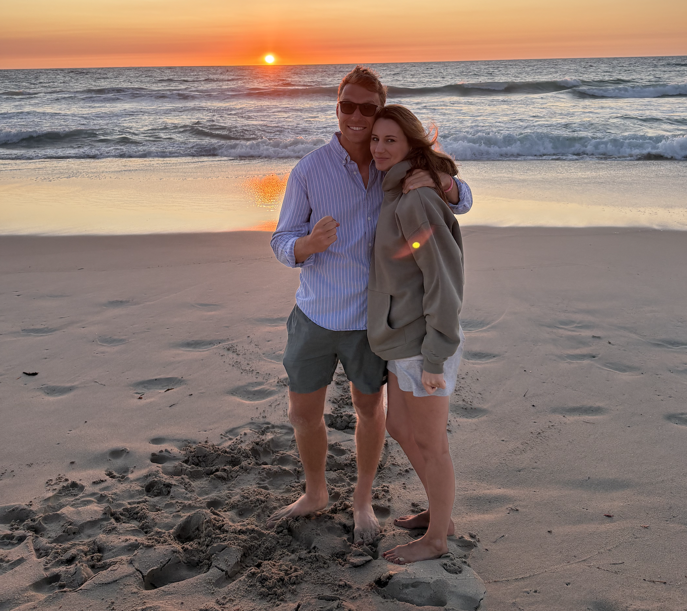 A couple together on a beach at sunset